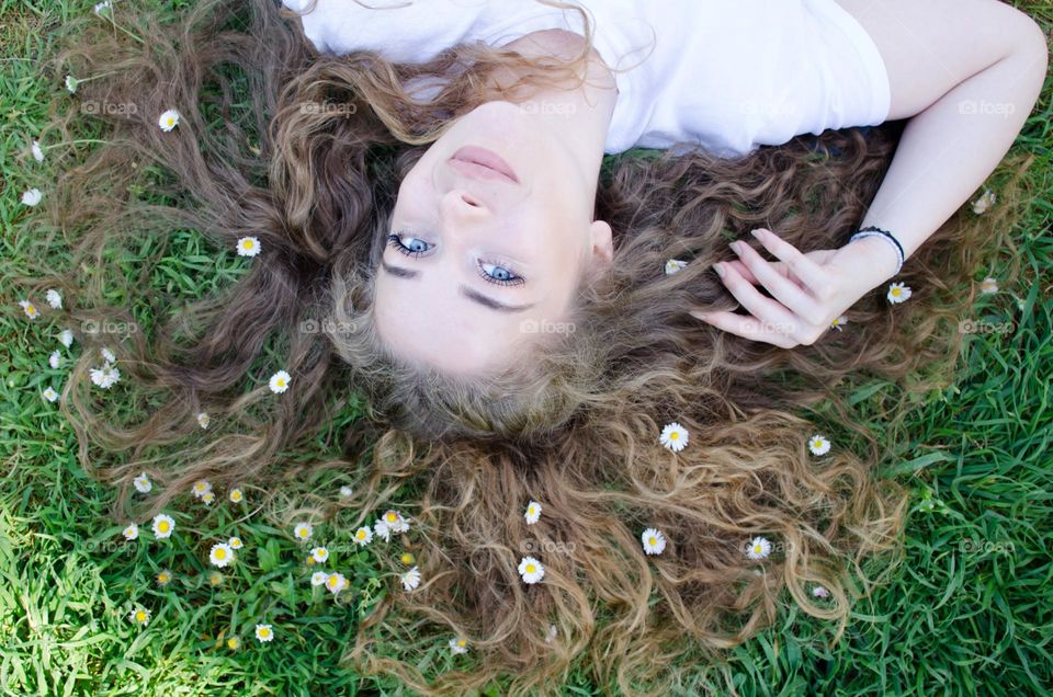 Portrait of a woman blonde with beautiful natural hair on background of daisies