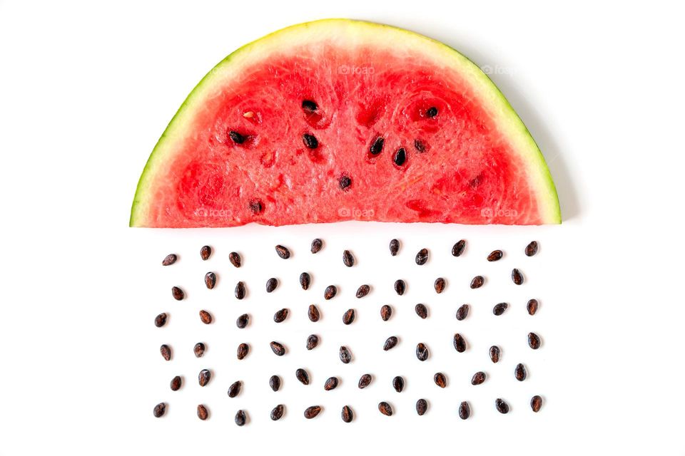 Juicy slice of watermelon isolated on white background with seeds as rain, creative concept