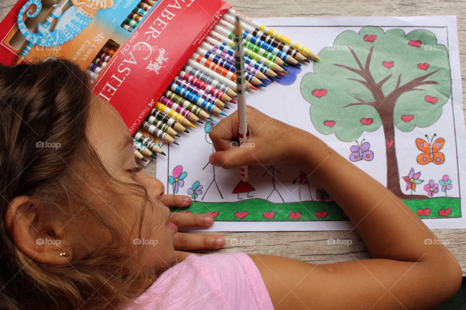 Girl coloring drawing with lapis Faber Castell