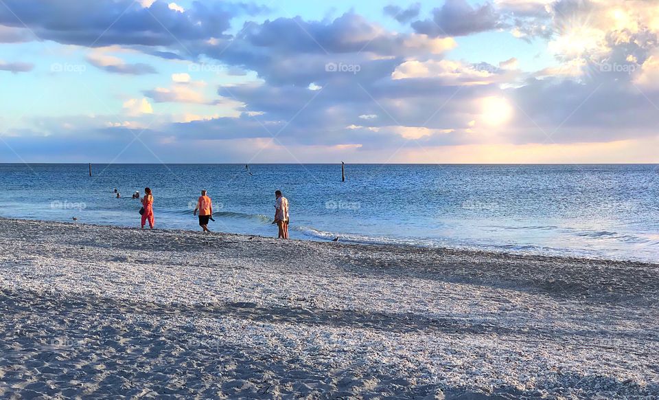 Family enjoying the waves , the beach and the pastel sunset.