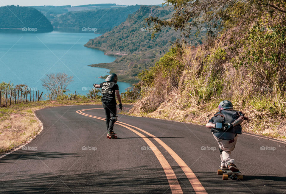 skatistas descendo estrada com paisagem bonita.