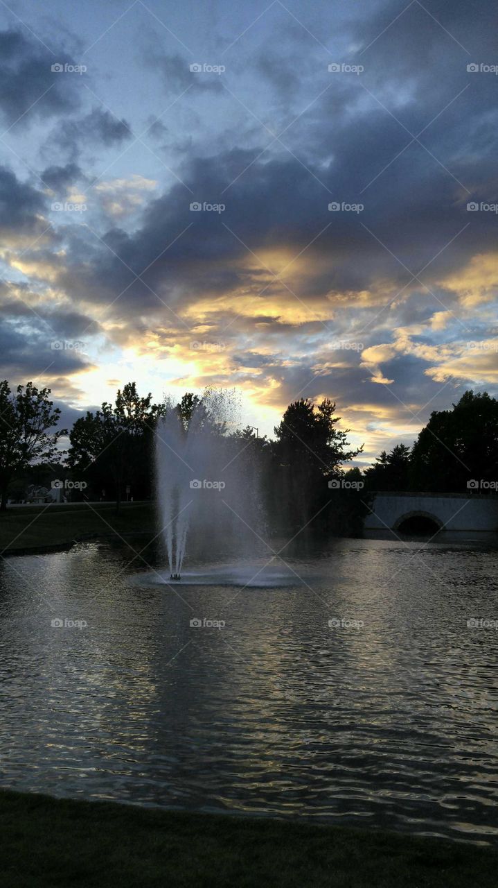 evening sunset with a fountain and clouds reflecting the sun