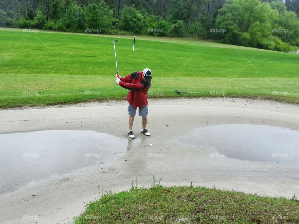 golfing in the rain with puddles in the sandtrap