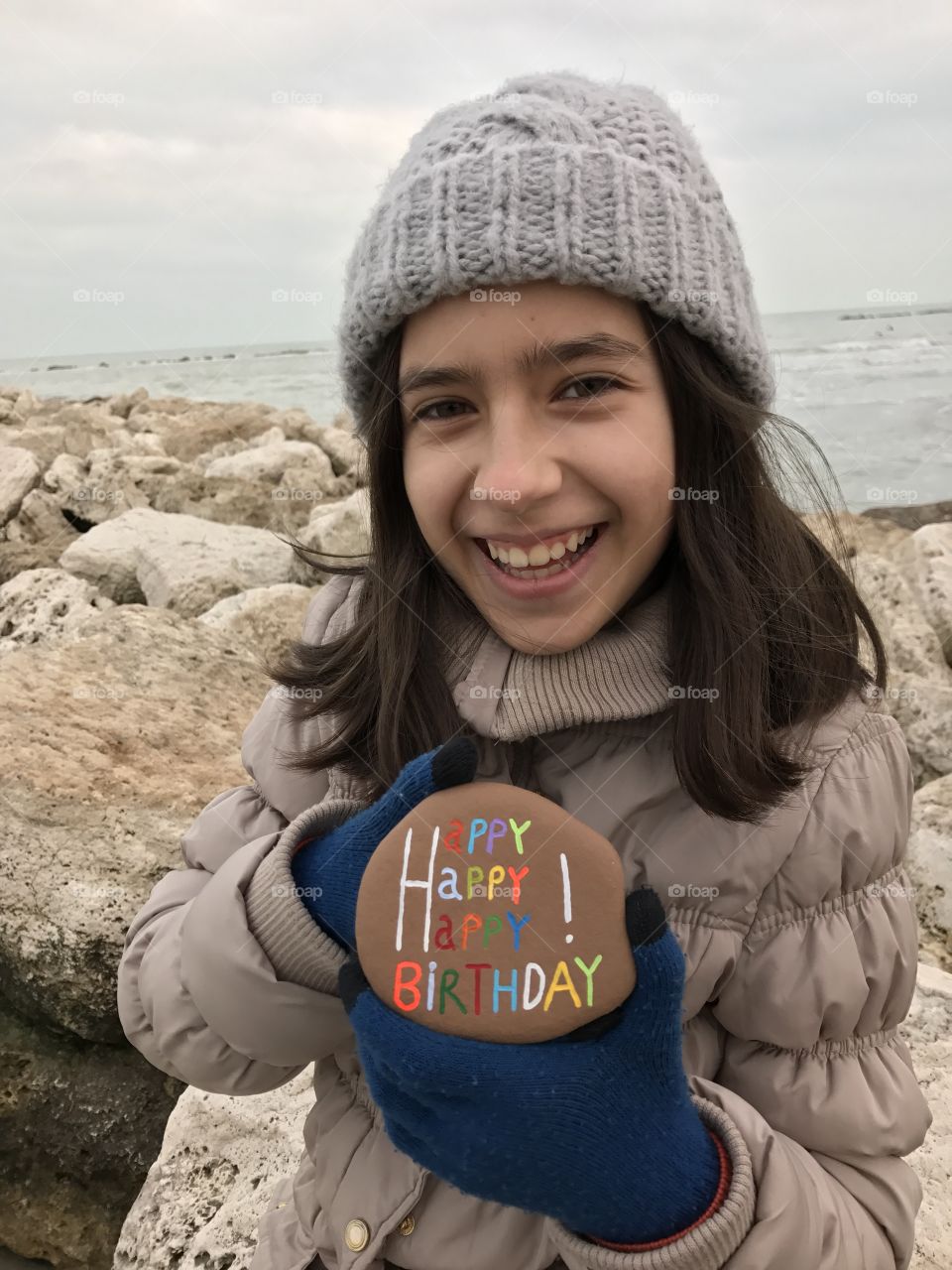 Girl holding pebble stone with birthday text at beach