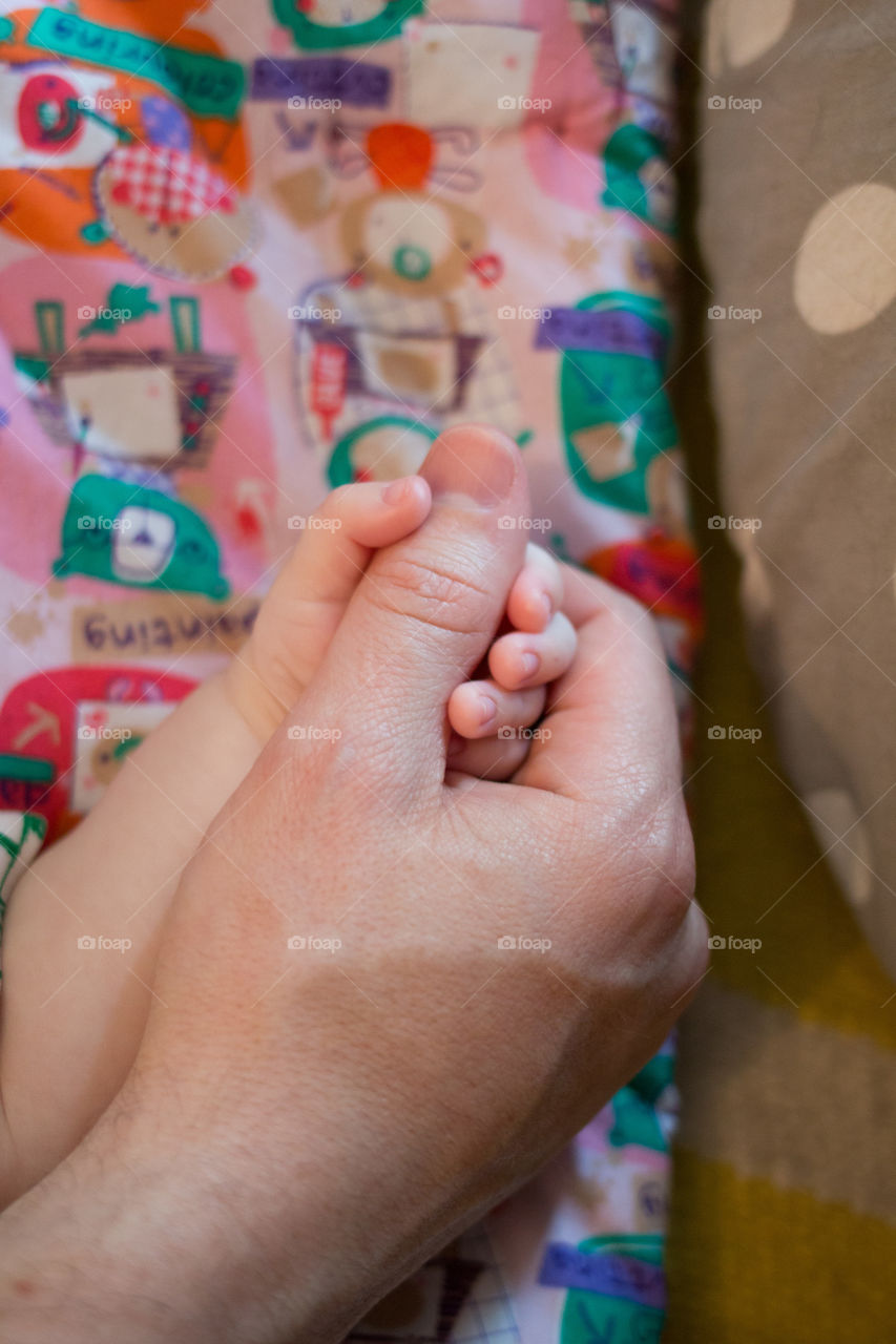 New born baby holding mother thumb