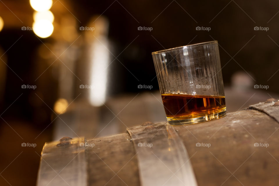 glass of whiskey on barrel. glass of whiskey on wooden barrel in distillery