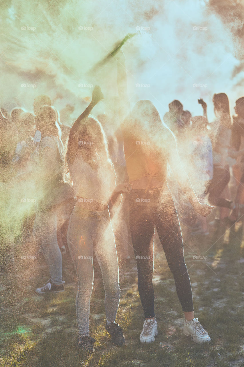 Portrait of happy smiling young girls with colorful paints on faces and clothes. Two friends spending time on holi color festival. Real people, authentic situations