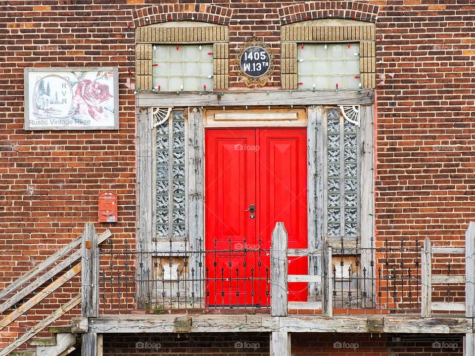 A beautiful freshly painted red door starkly contrasts the dull woodwork around it