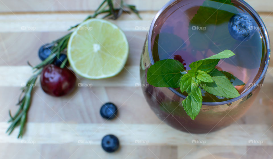 High angle view of fresh homemade blueberry, Rosemary mint, citrus, cherry flavored water on wood table with healthy drink ingredients - summer drink photography