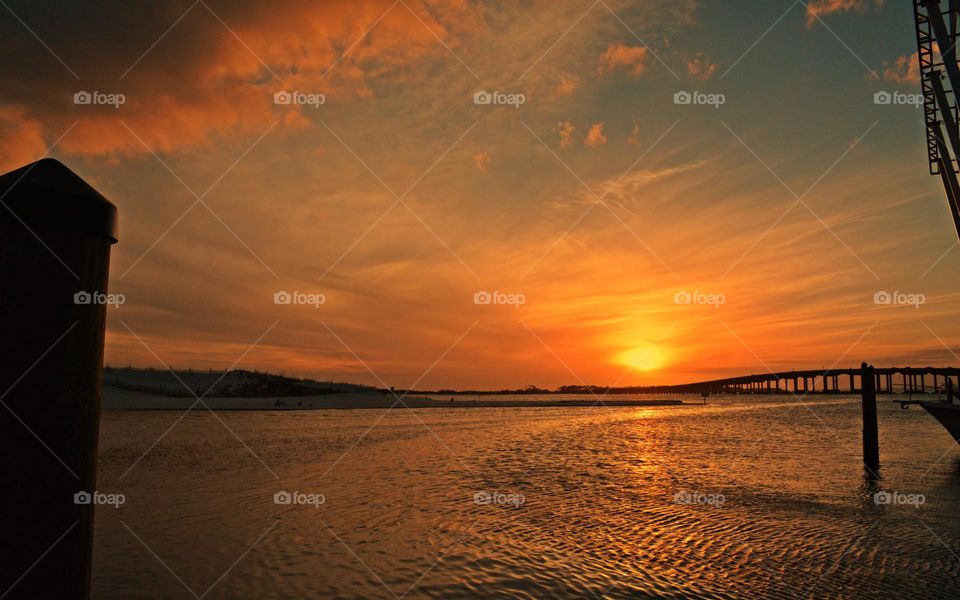 The sun, a fiery orb, looks like it’s gradually receding into the waters below. The sky consists of an assortment of shades, a blend of reds, oranges and yellows