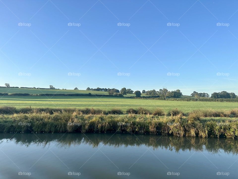 Final day of narrowboat cruising on Oxford canal near Napton early morning clear sky lovely weather English countryside green fields late summer vacation