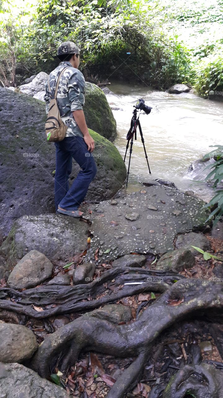 Photographer on location shooting long exposure river flowing