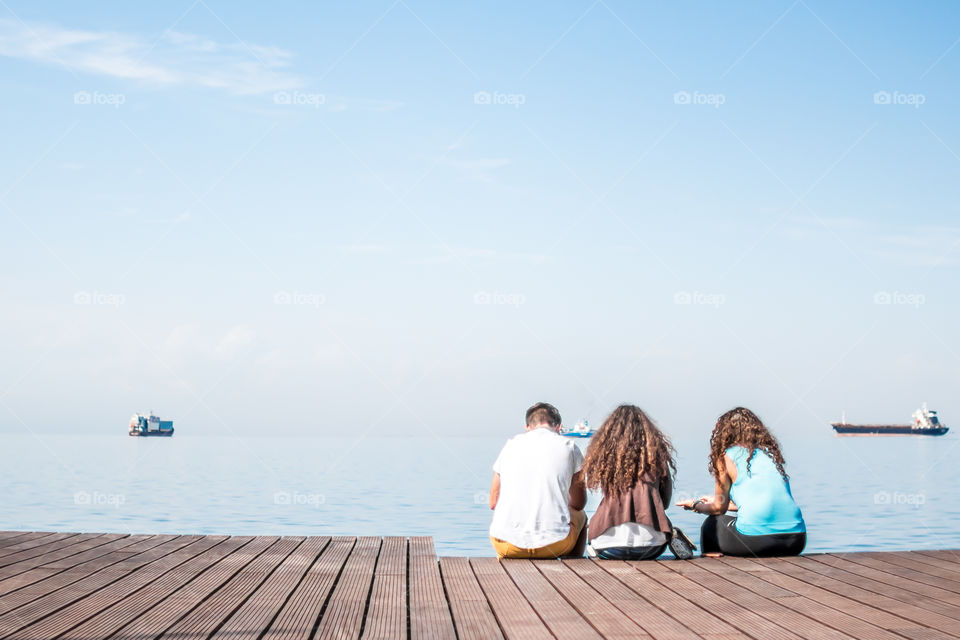 Friends Sitting On Wooden Dock
