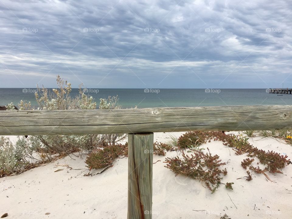 Remote pristine beach with turquoise waters in south Australia; foreground weathered wood fence