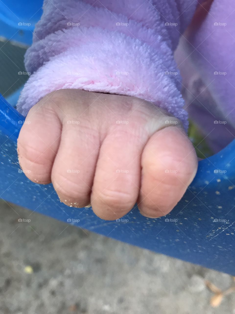 Baby girl fingers holding on to a playground tunnel