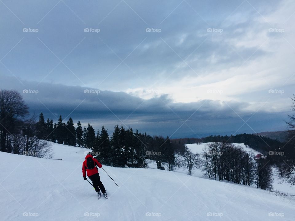 Skier on the slope with grey storm clouds above