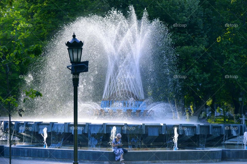 a large beautiful fountain of many jets of water in a green summer park