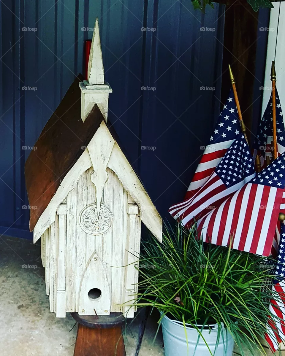 Summertime porch display with birdhouse and American flags.