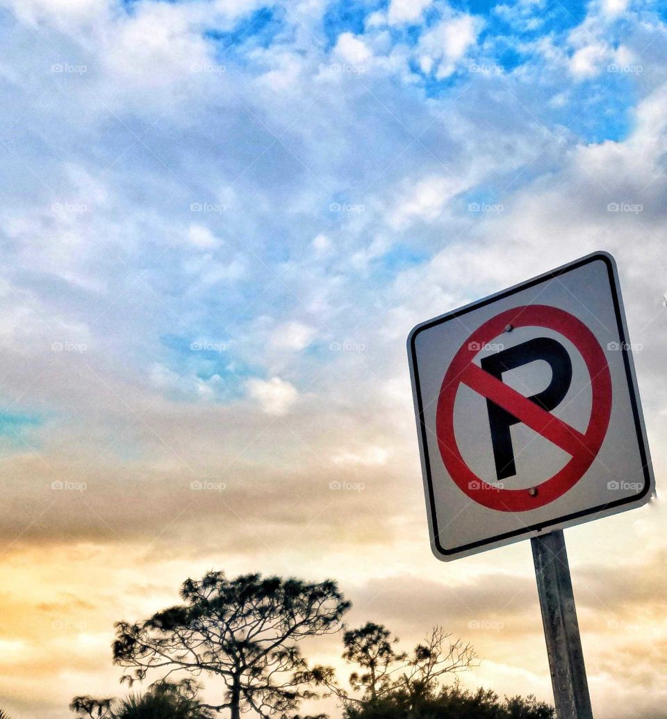 No parking sign against dramatic blue and gold sky with clouds