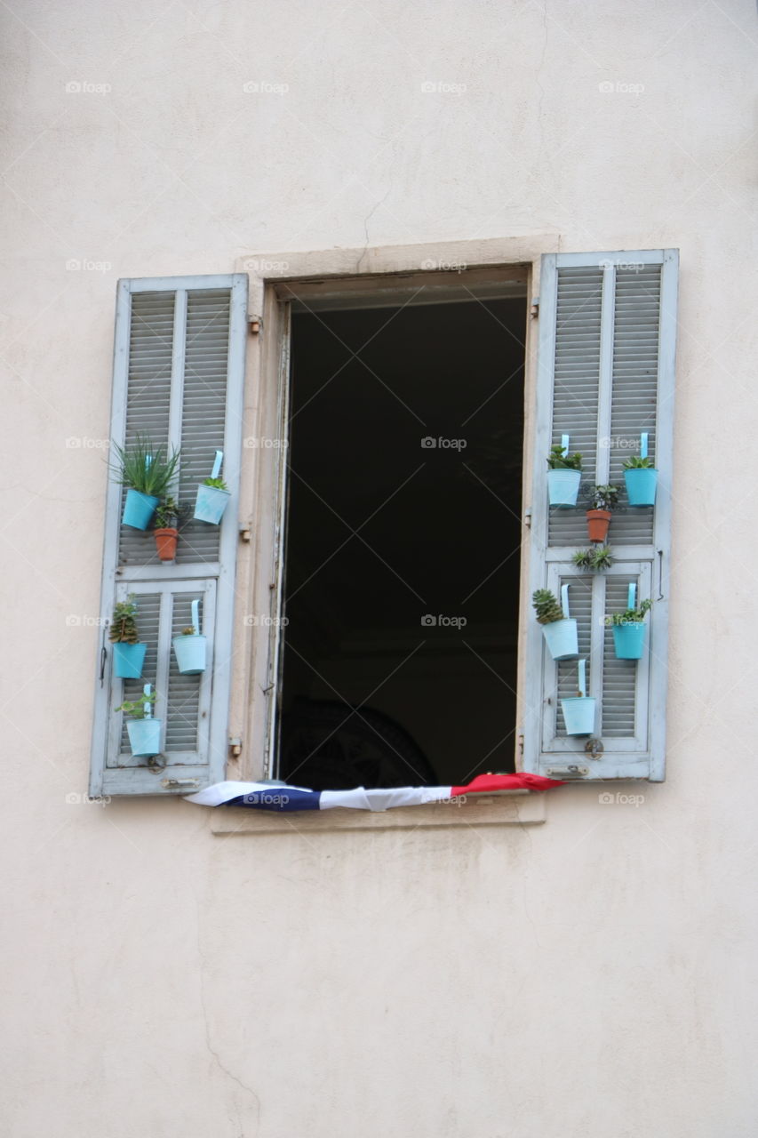 Little pots with plants hanged on the sunshades of an old building 