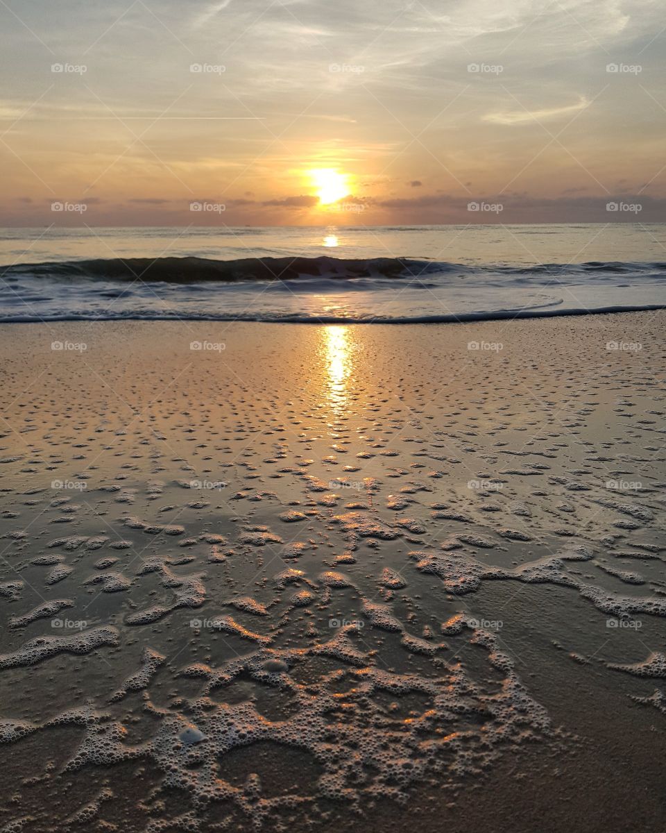 Scenic view of beach against sunrise sky