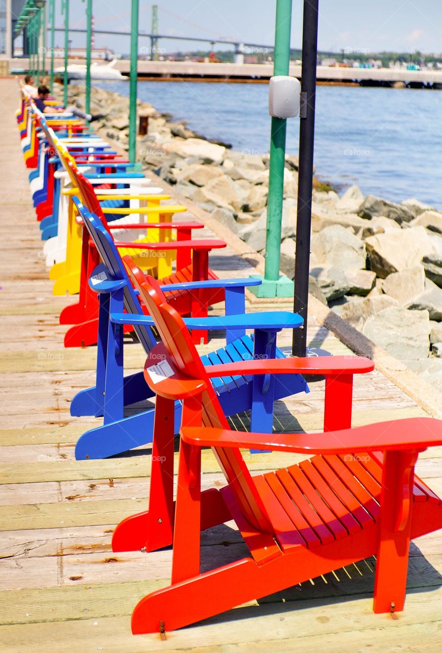 Rainbow coloured Muskoka chairs in Halifax bay.