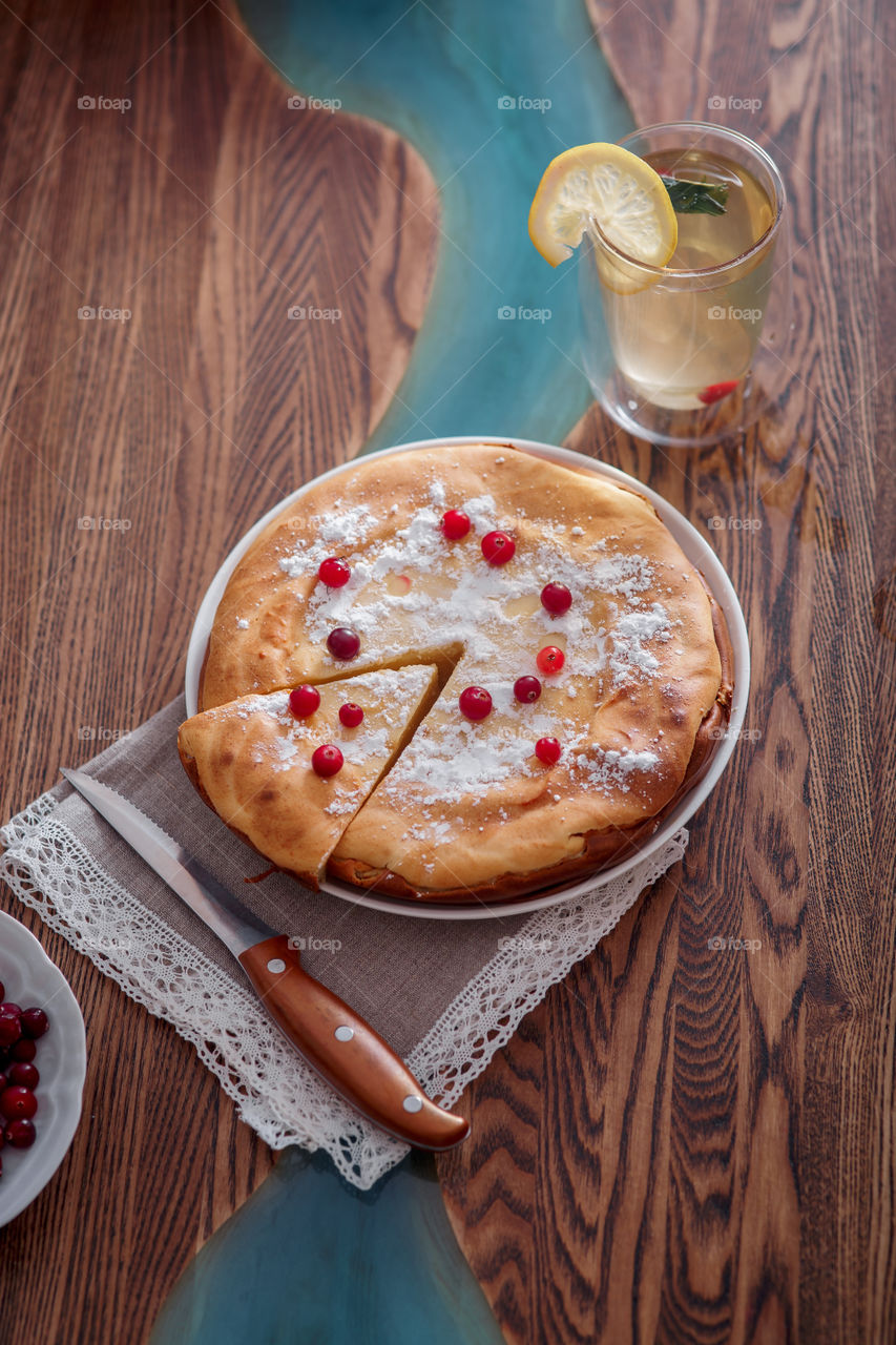 Cheesecake with cranberries and sugar on wooden background