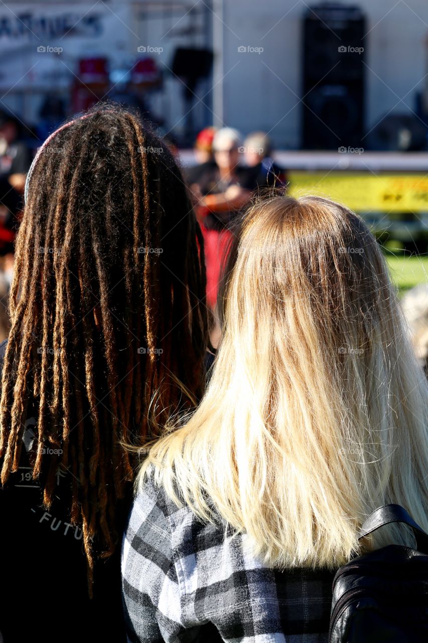 Male and female couple from behind at music festival. Dreadlocks and long blonde hair 