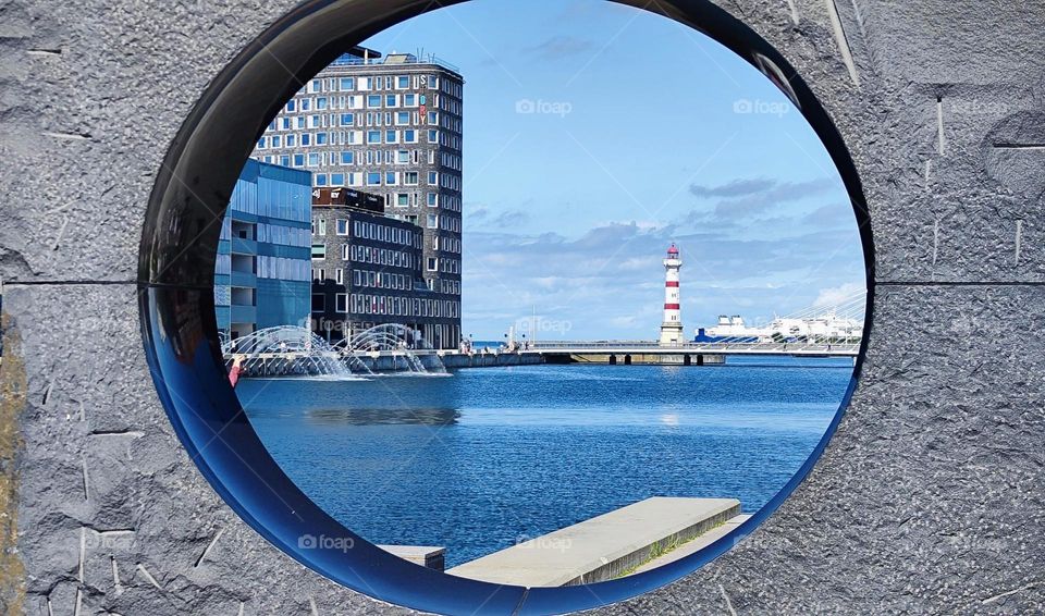 Through this beautiful buoy we see the beach of “Malmö”, “Sweden” by the “Baltic Sea”, a traditional red & white striped lighthouse and modern architecture. The temperatures here are moderate and not too hot in the summer. 2023. Hypnotic Productions
