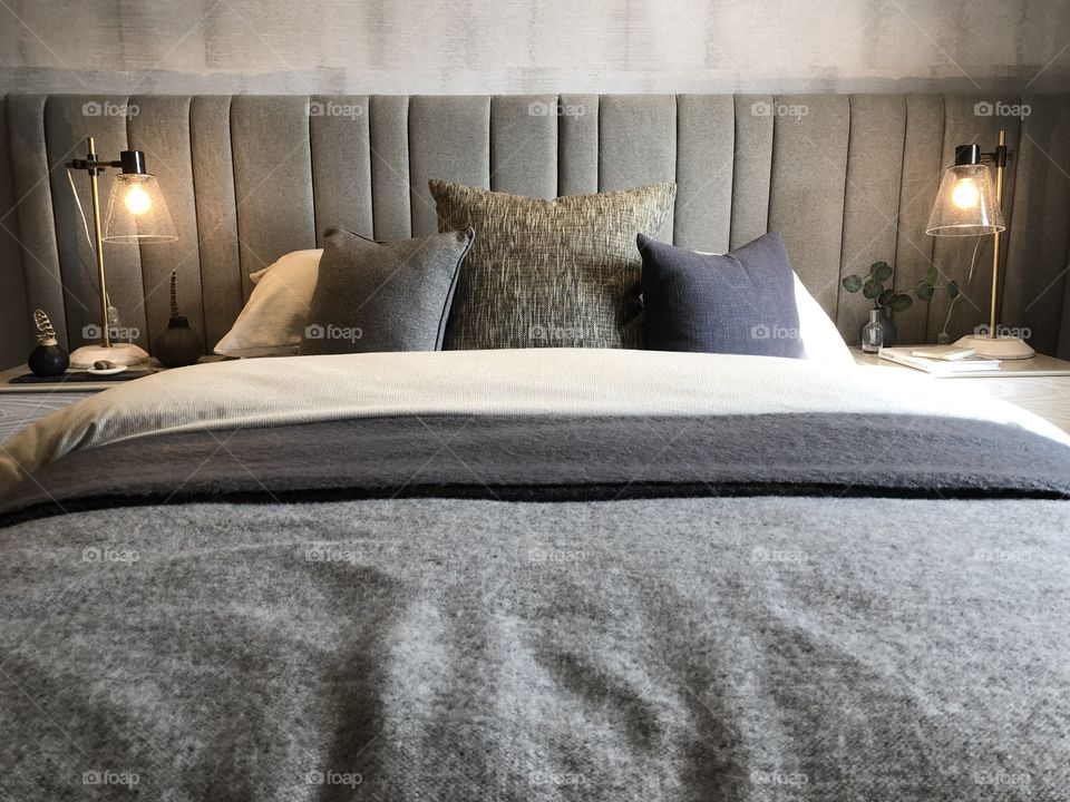 Gorgeous bedroom with pillow and headboard view in grey shades and tones. Warm and comforting