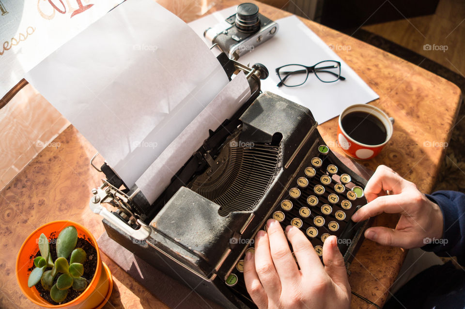 A young writer is writing a new book on an old typewriter.