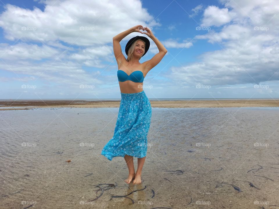 Woman making heart shape on sandy beach