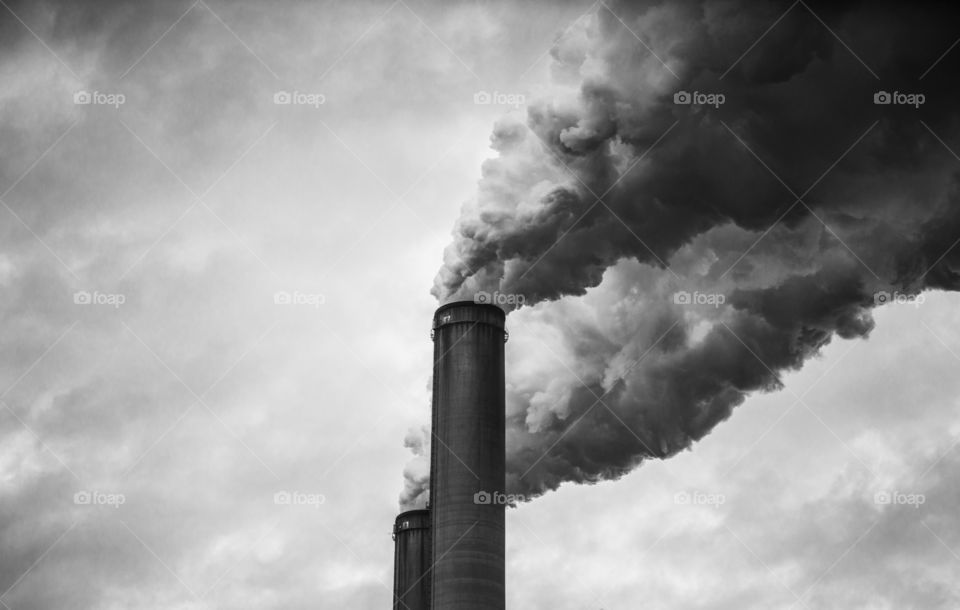 Smokestacks polluting atmosphere in black and white