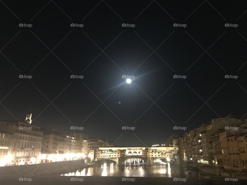 The lit up ponte vecchio with the moon lighting up the Arno at night.