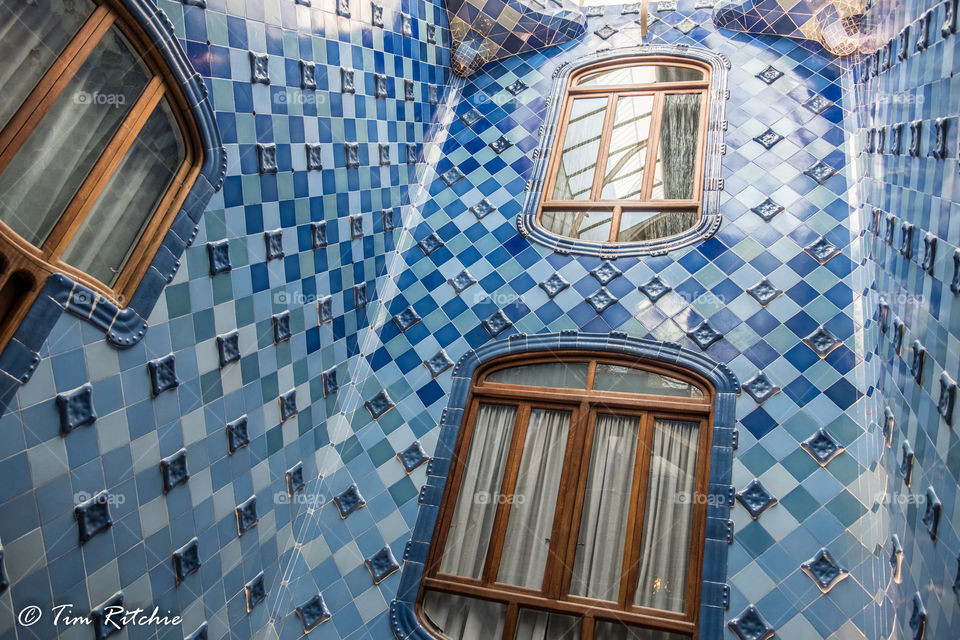The light well in the centre of Gaudi’s astonishing Casa Batllo, Barcelona, Catalunya, Spain. The tiles nearer the roof are darker, then lighter as you look down to give the appearance of even light