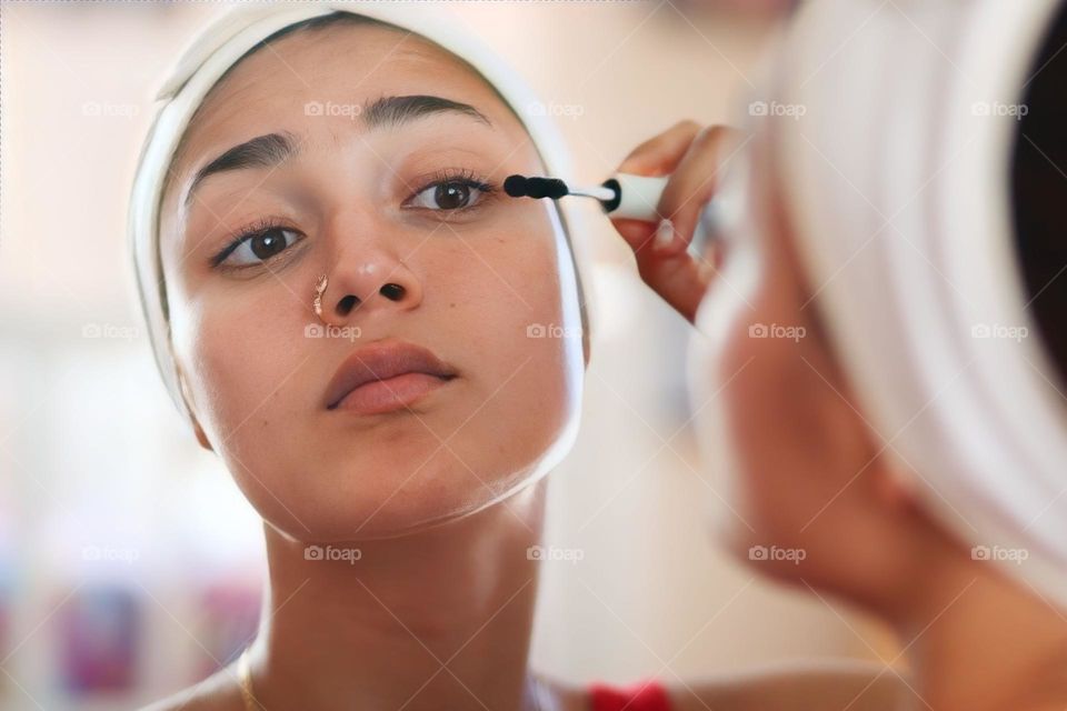 Young beautiful woman is using the mascara