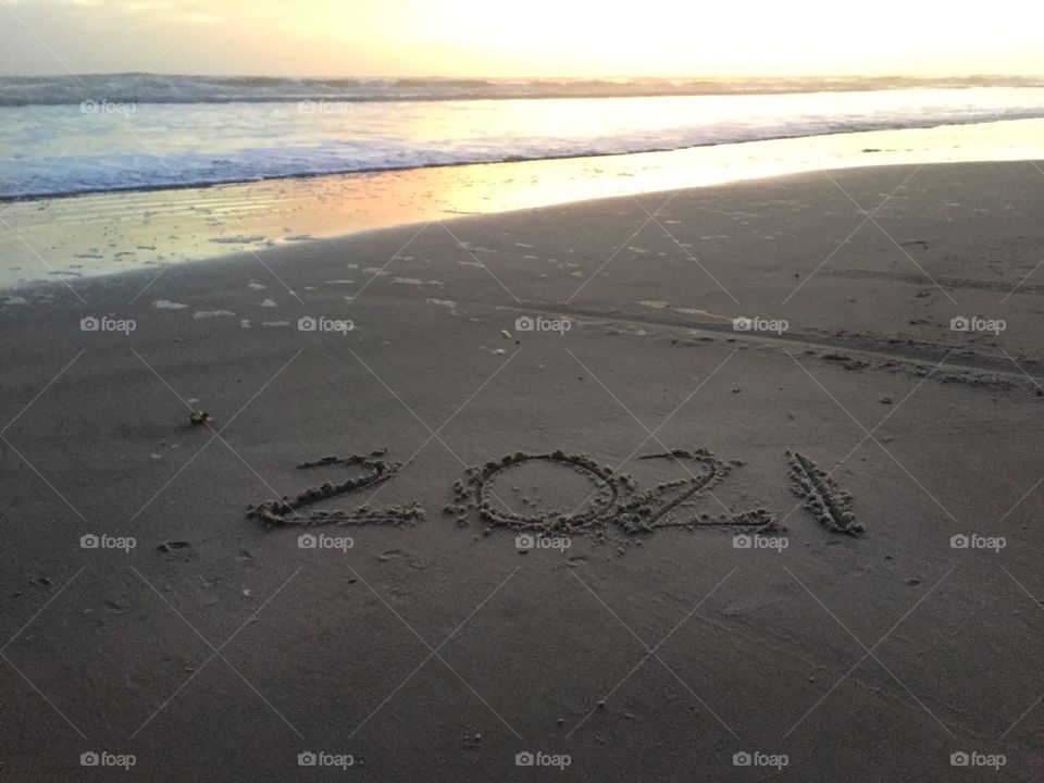 The new year 2021 written in the sand at the beach at sunrise 