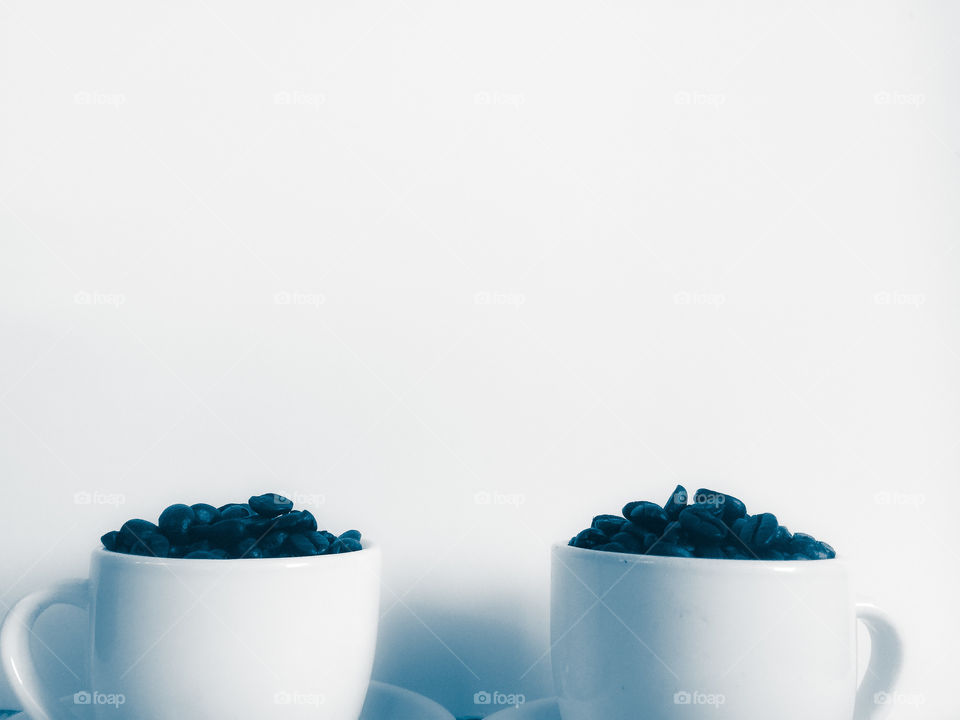 Creative shot of espresso beans in white mugs