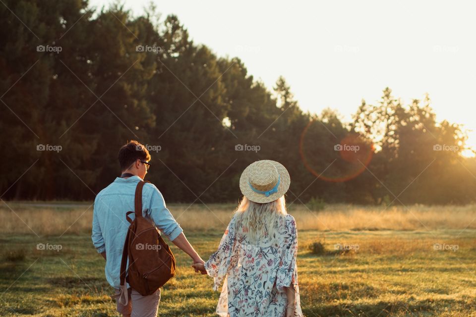 Loving couple hold hands and go to the sunrise.