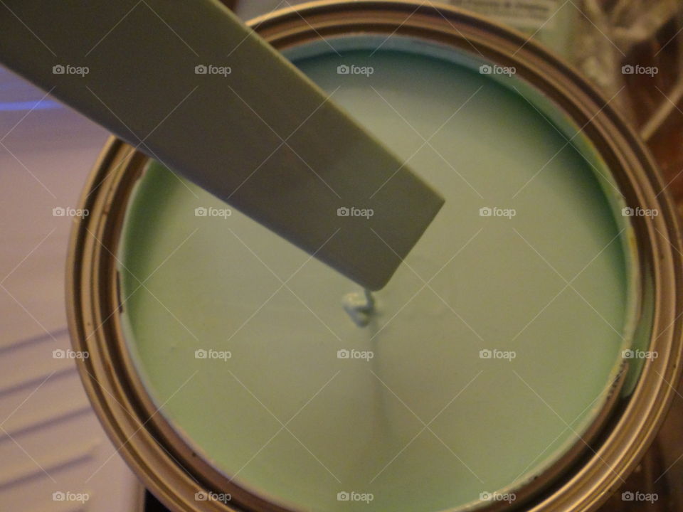 Paint. Mint green paint dripping back in to the paint can from the paint stirrer. 