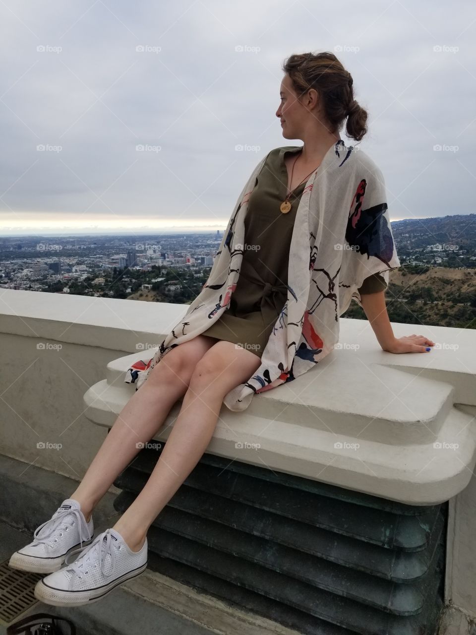 Girl in white and green looking out over Los Angeles