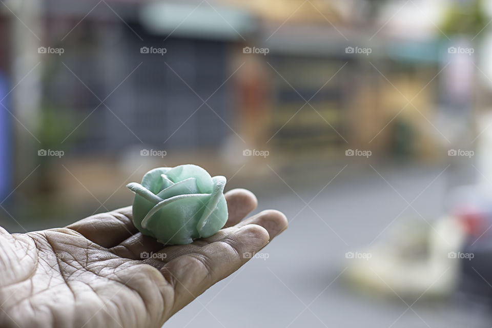 The hand holding the Thai dessert flower green or Aalaw candy.