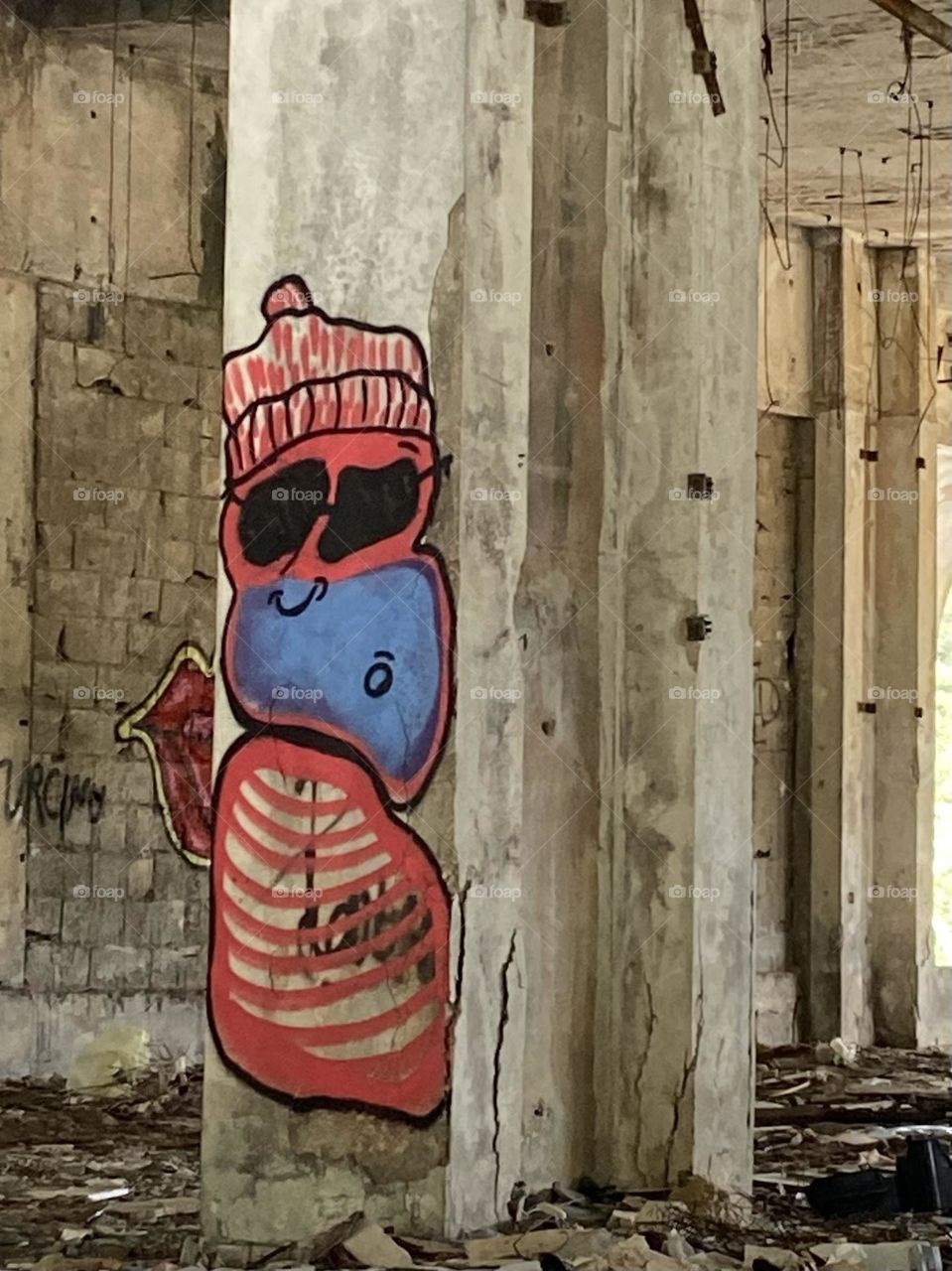 A cheerful colorful smiley street art creature in an old building destroyed in a long ago homeland war.