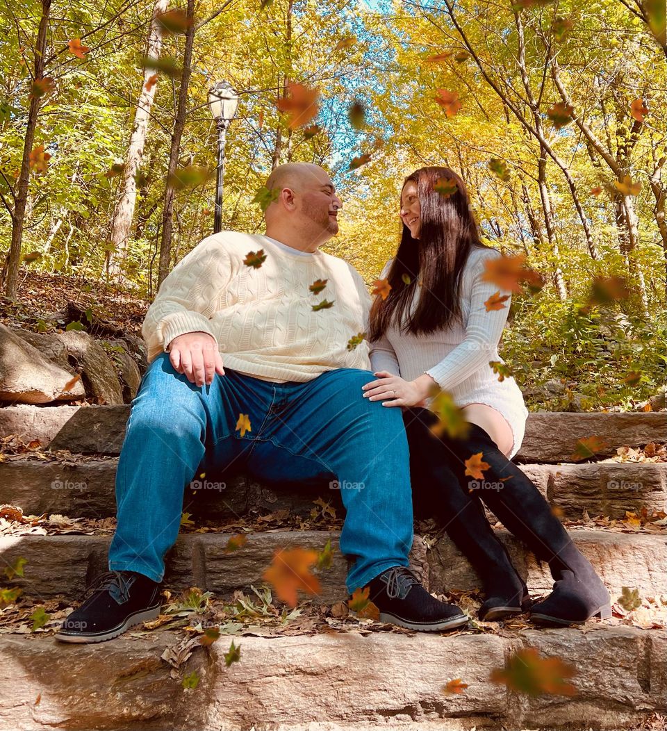 Couple in Demi saison clothing surrounded by beautiful falling fall leaves