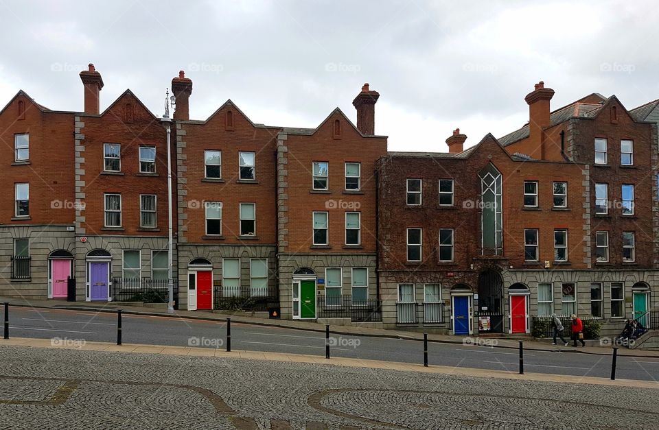 Living in harmony, side by side houses on angled Street in Dublin, Ireland, Europe, with different unique colored front doors on cloudy day