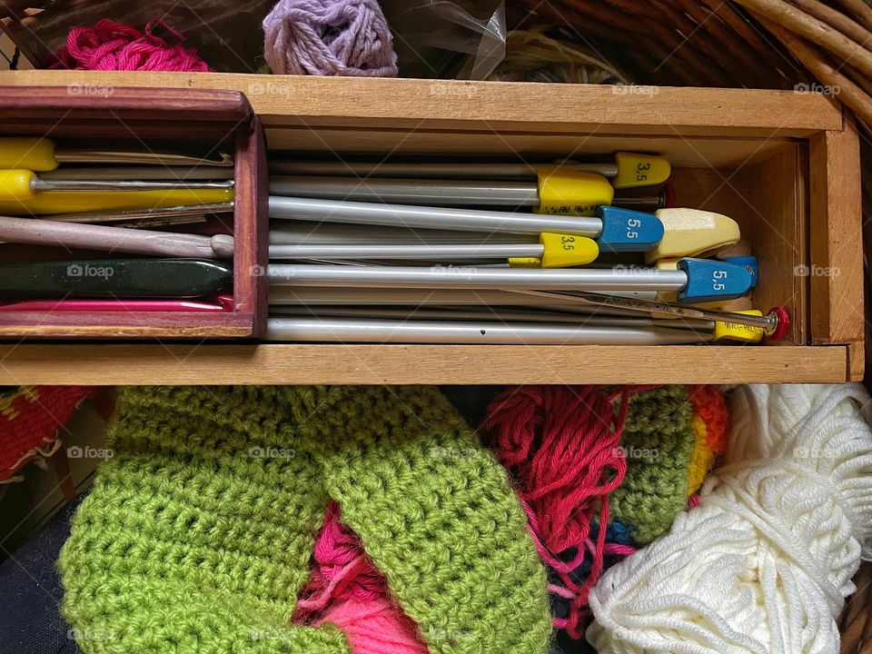 Close up of knitting and crochet hooks on balls of yarn in a basket