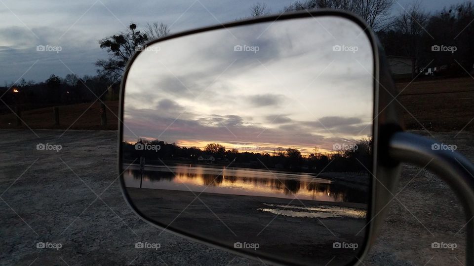 Reflections in the mirror of the reflection of trees and sunset in the water