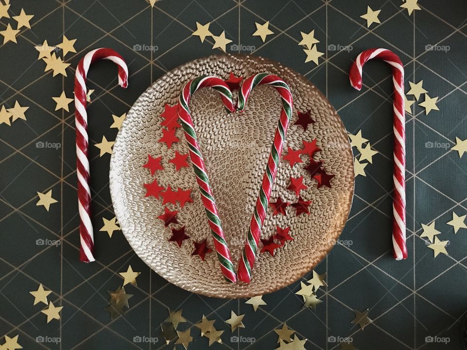golden plate on the table with christmas canes and golden stars