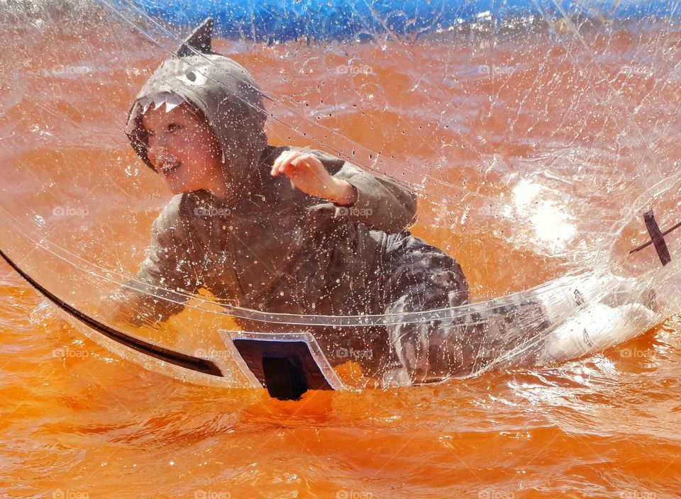 Boy In A Bubble. Boy Splashing Inside A Plastic Bubble Water Ride
