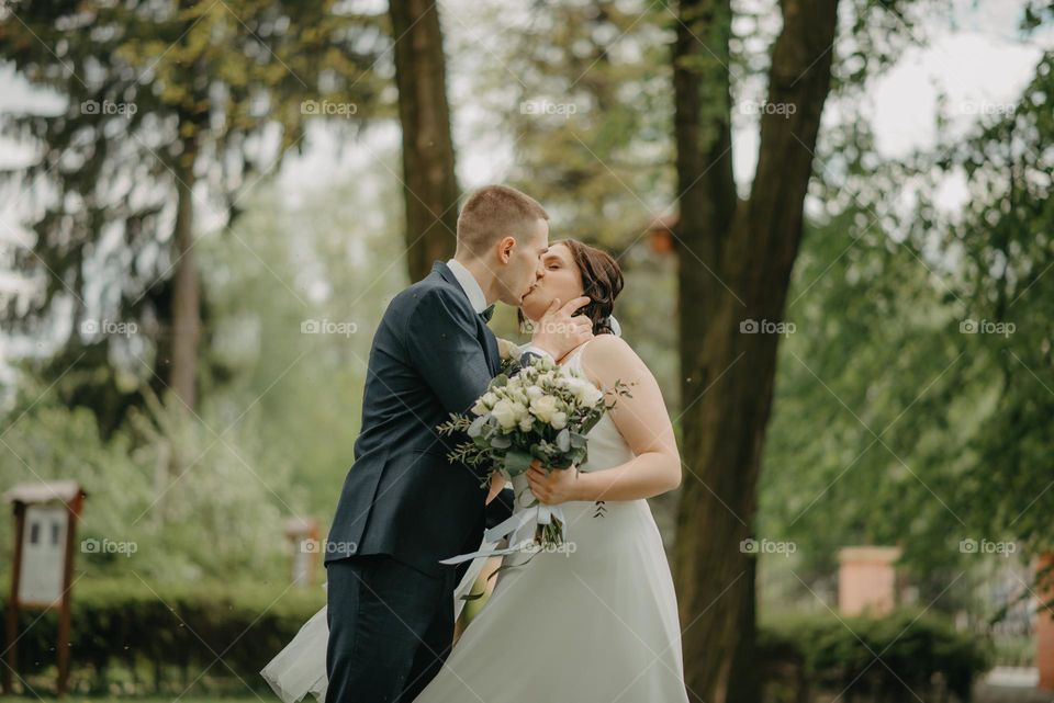 A sweet kiss of the bride and groom among the greenery